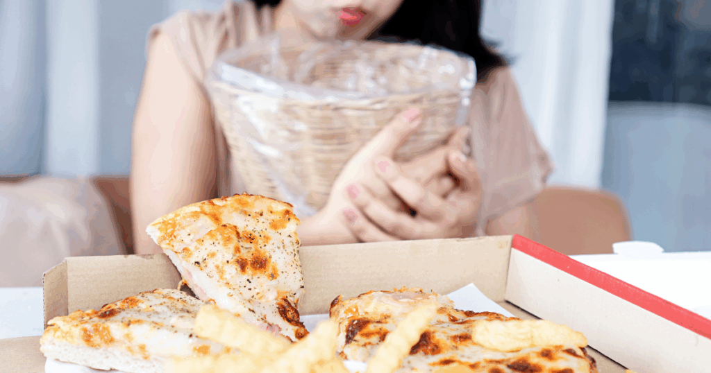 Woman eating pizza while holding a glass of water, showing hydration’s role in controlling hunger and supporting weight loss